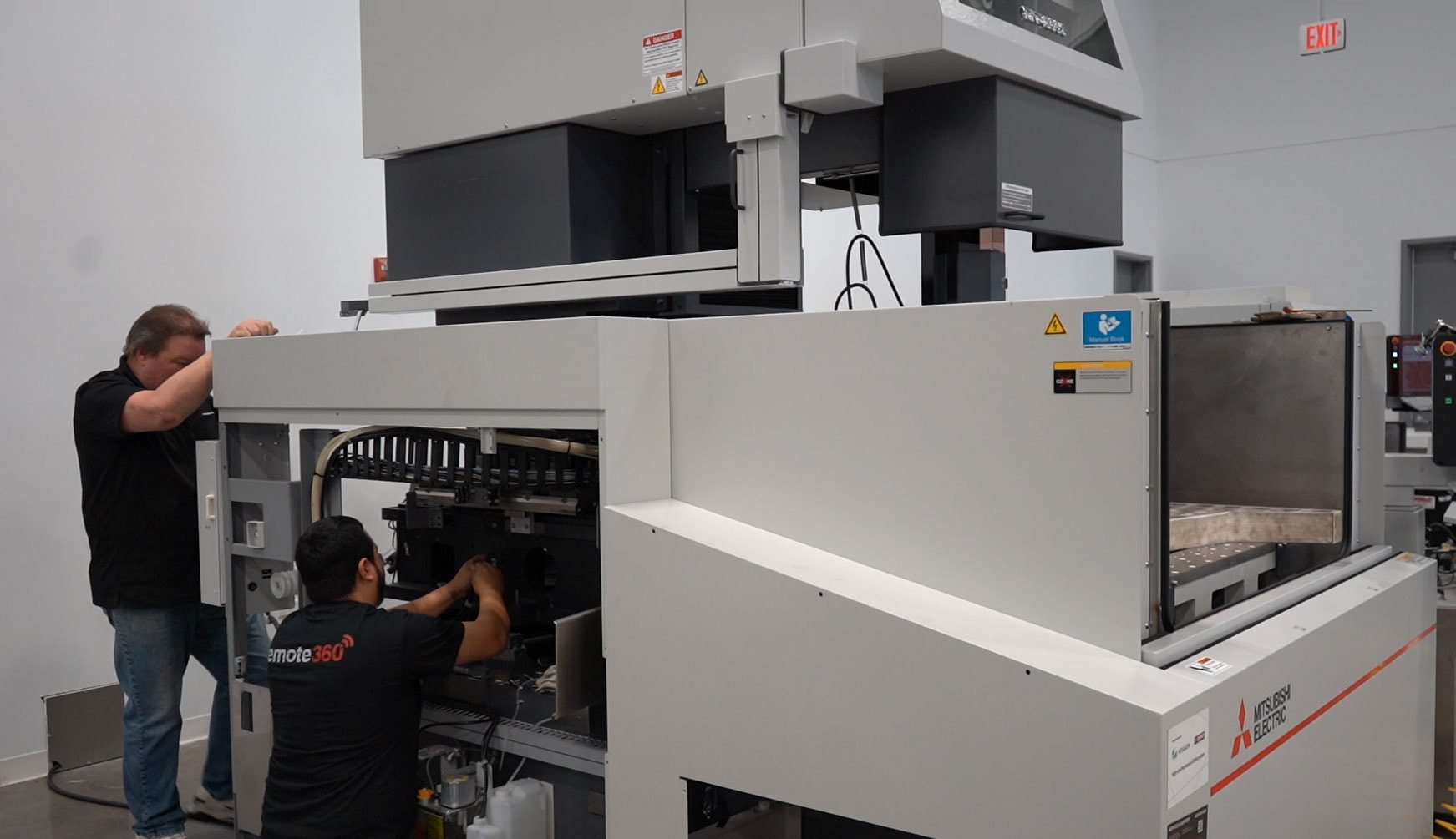 Technicians operating an industrial wire EDM machine